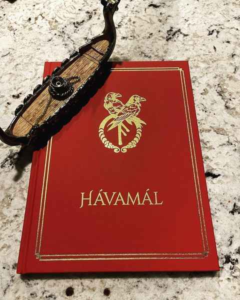 A picture of book Havamal with a wooden boat over it