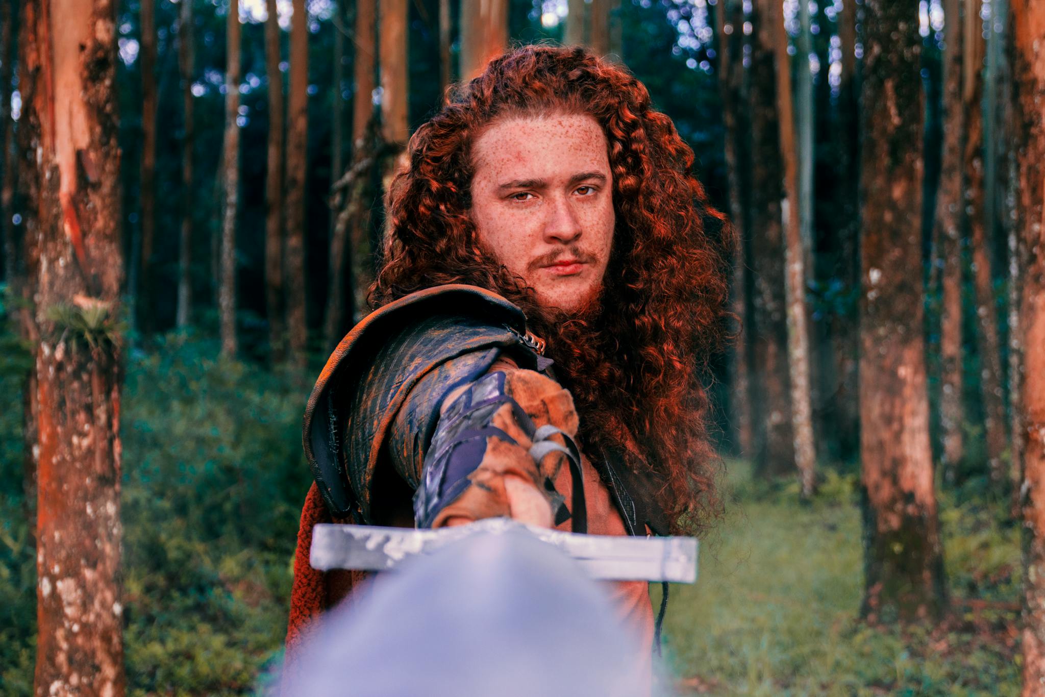 Portrait of a Viking warrior with red hair holding a sword.